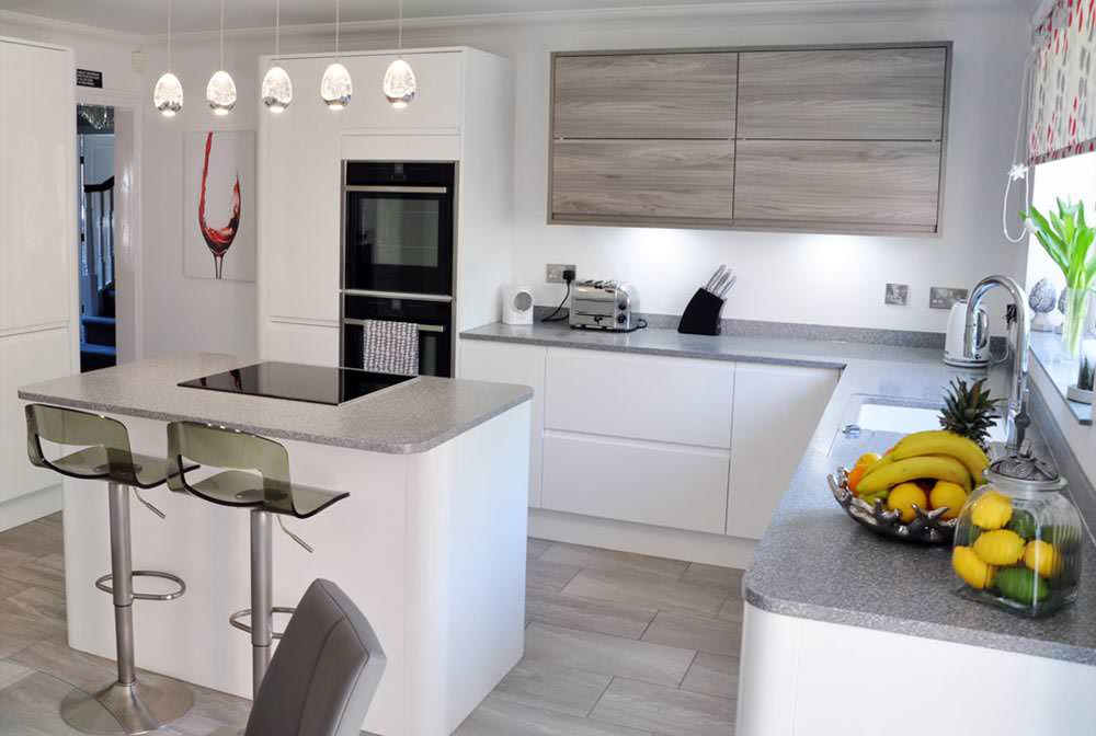 دکوراسیون آشپزخانه کوچک و مدرن با کابینت های سفید که در مرکز آن جزیره ثابت برای اضافه کردن به سطح اپن نصب شده است